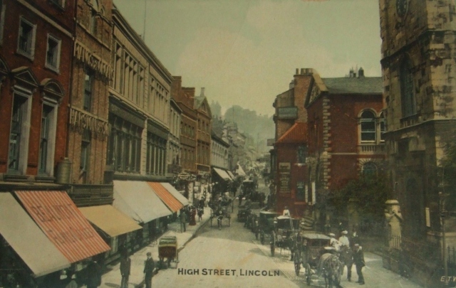 Early 1900s postcard showing Lincoln High Street with St Peter at Arches and the Butter Market on the right.