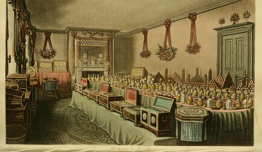 Interior of the shop of Alex Ross, perfumer in London; a large table displays the many perfume bottles and scents on offer, wooden chests on bench next to table contain further goods; garlands of flowers hang from walls; illustration to Ackermann's 'Repository of Arts', part 1 or 85, series 2, vol 1. 1816. British Museum